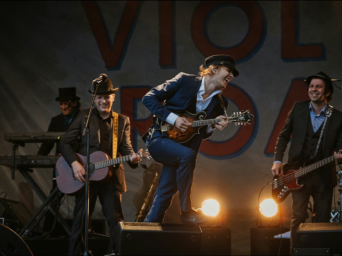 Full band playing live on stage under warm stage lights